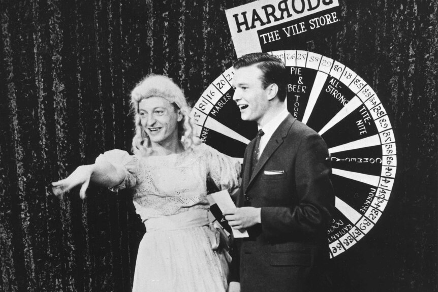 Graham Kennedy wears a dress and gestures to the crowd alongside Bert Newton on a New Year's Eve show in 1959.