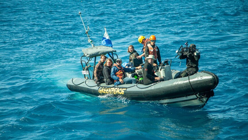 Eight people sit in an inflatable Zodiac boat.