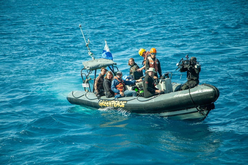 Eight people sit in an inflatable Zodiac boat.