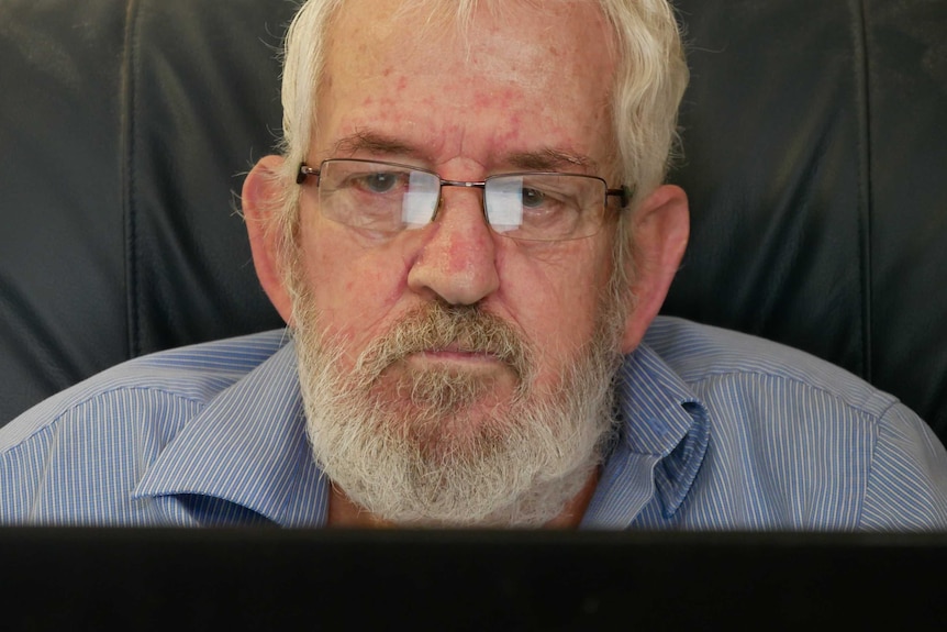 A portrait shot of an elderly man wearing glasses