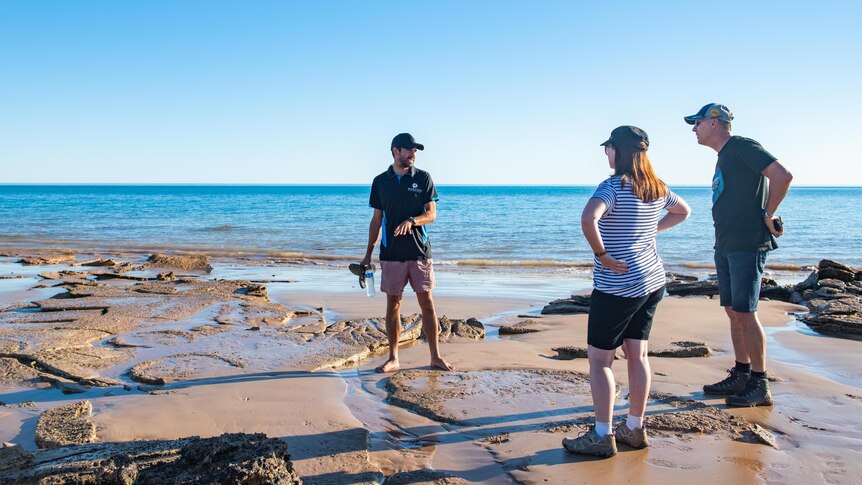 A tour guide talks to two tourists (a woman and a man) at Roebuck Bay in Western Australia 