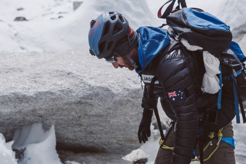 A man in snow and climbing gear treks icy ground