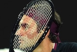 A male tennis player's head is obscured by his racquet strings as he prepares to play a backhand volley at the Australian Open.