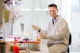 A man wearing a white coat in a research lab. 