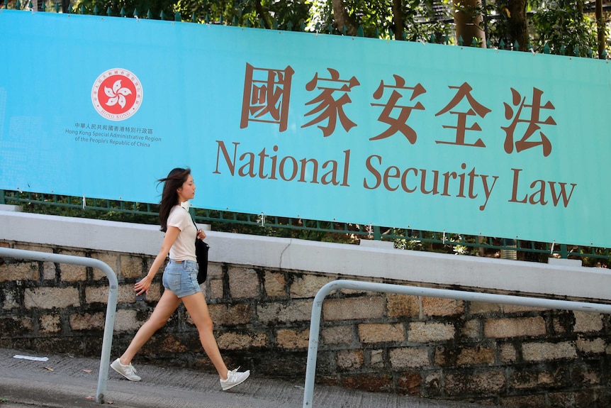 A woman walks past a banner promoting the National Security Law for Hong Kong