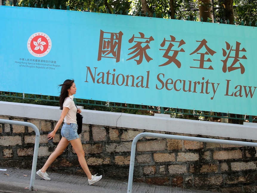 A woman walks past a promotional banner of the national security law for Hong Kong