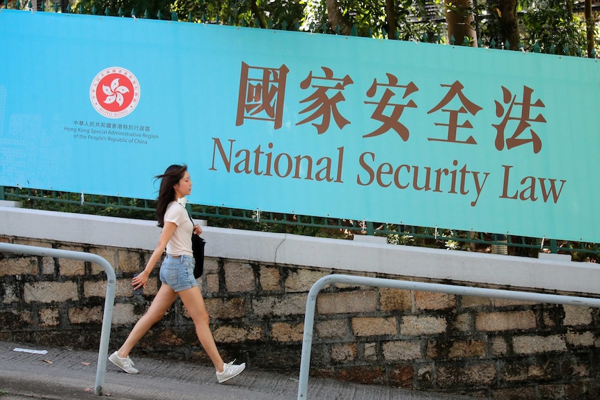 A woman walks past a promotional banner of the national security law for Hong Kong