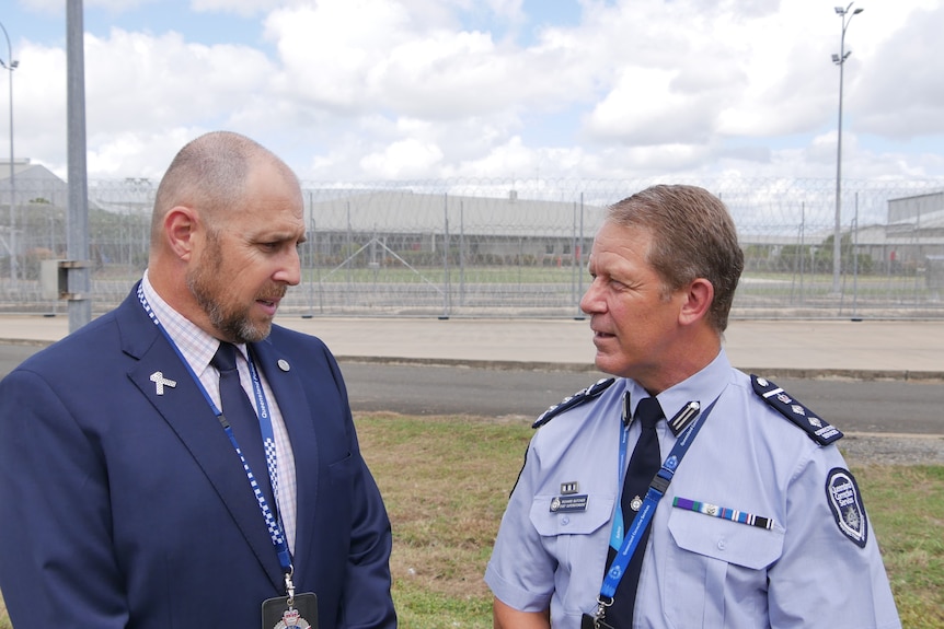 Two men in uniforms chatting in front of a prison building