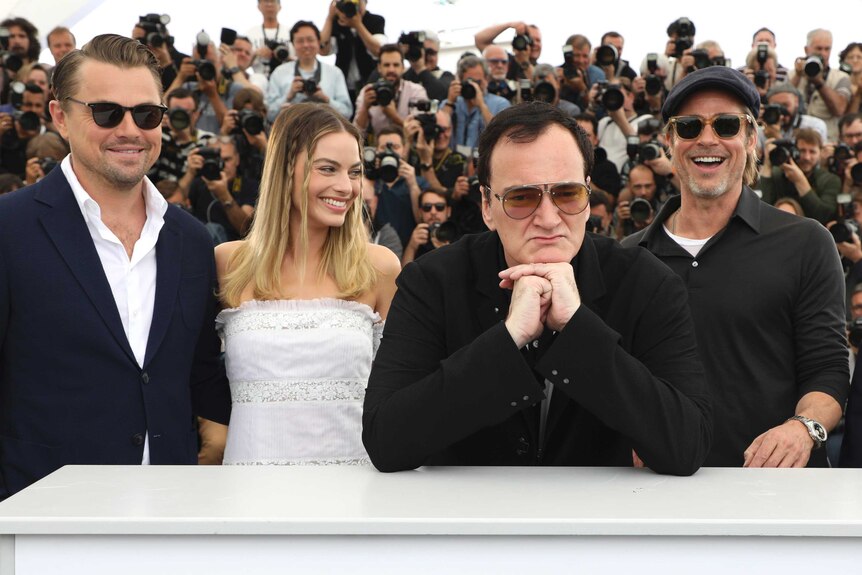 Actors Leonardo DiCaprio, from left, Margot Robbie, director Quentin Tarantino and actor Brad Pitt are behind a Cannes sign.