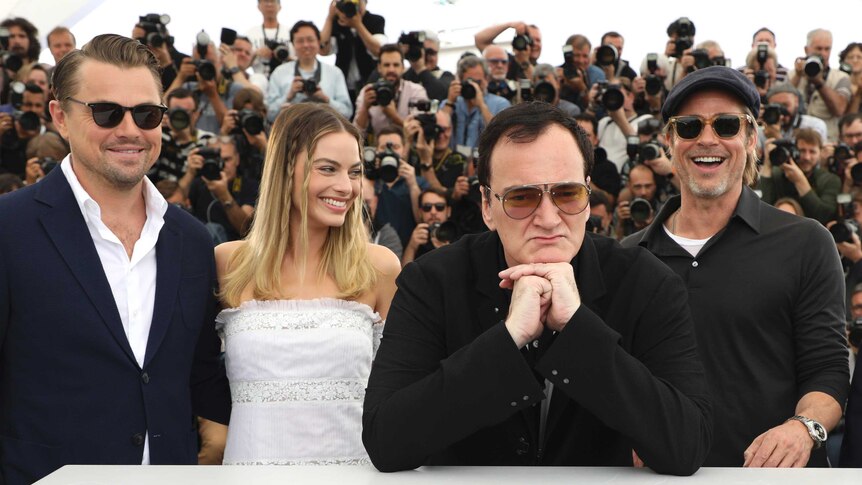 Actors Leonardo DiCaprio, from left, Margot Robbie, director Quentin Tarantino and actor Brad Pitt are behind a Cannes sign.