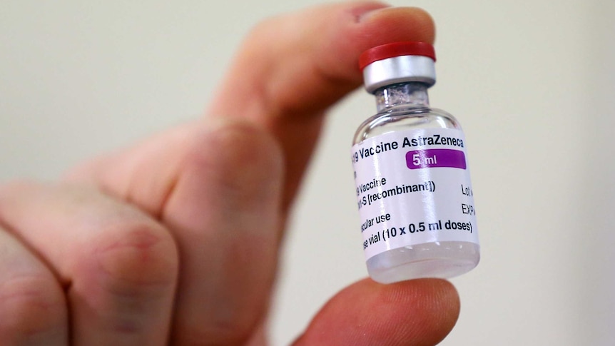 A vial of AstraZeneca vaccine is held up.