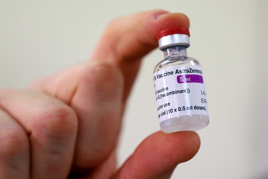 A vial of AstraZeneca vaccine is held up.