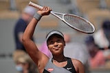 Women's tennis star Naomi Osaka waves her racquet above her head to salute the crowd after a match at the French Open.