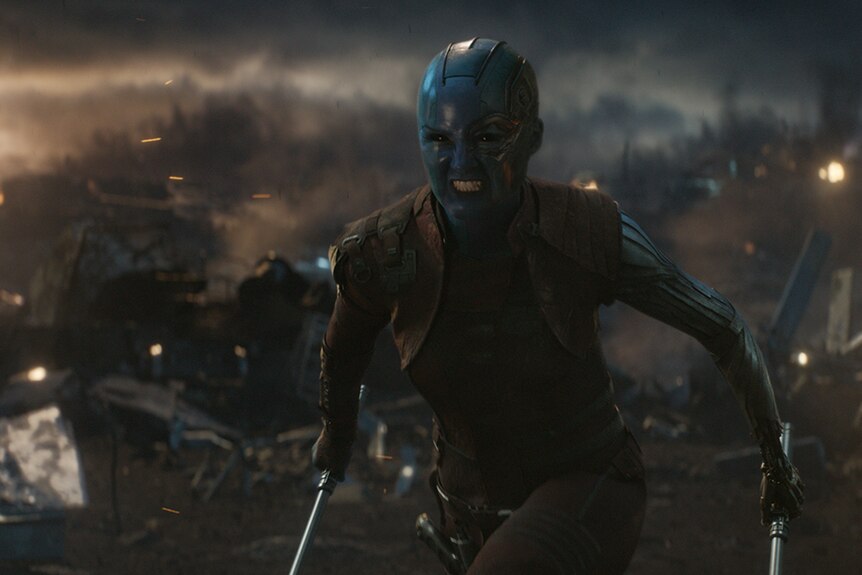 Colour still of Karen Gillan as Nebula in aggressively moving forward on battlefield in 2019 film Avengers: Endgame.