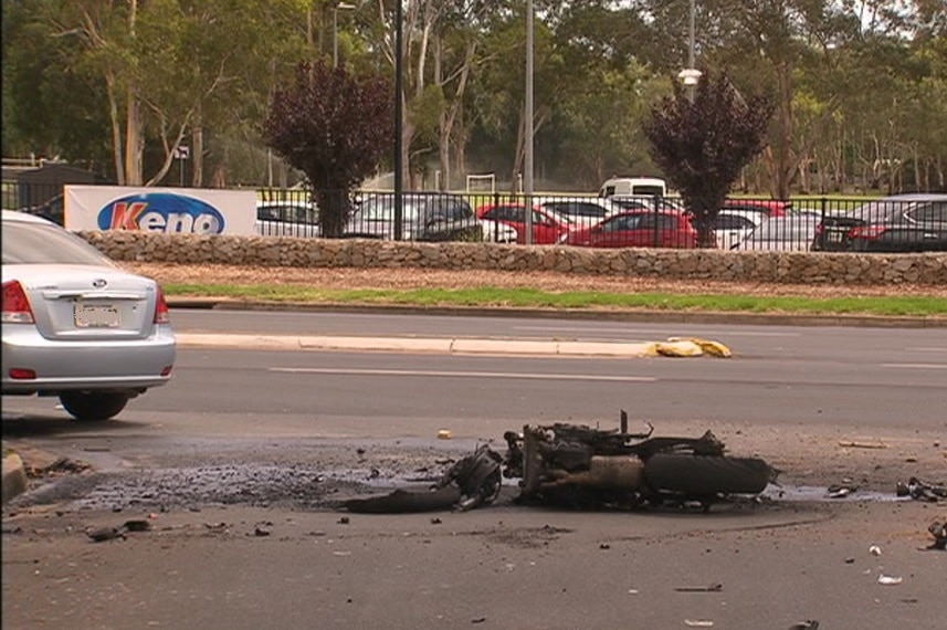 A silver vehicle and a damaged motorcycle on a road