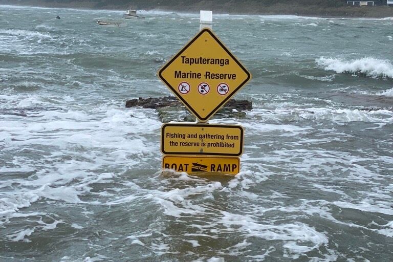 Water covers most of a boat ramp sign.