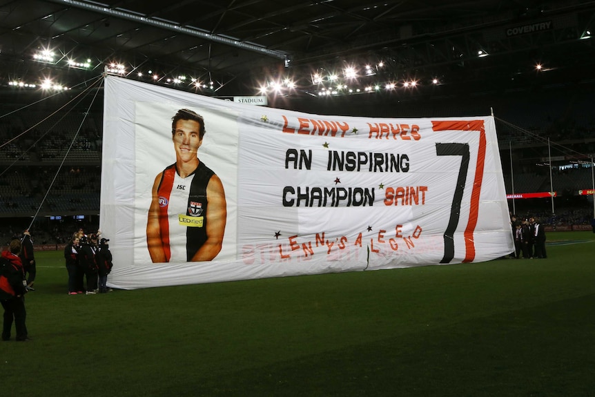 AFL fans raise a banner before a game with the message: "Lenny Hayes an inspiring champion Saint".