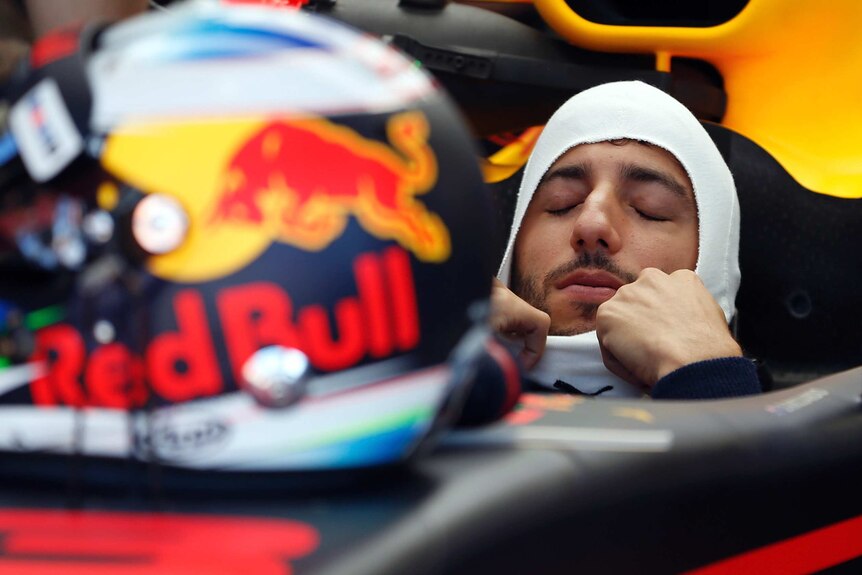 Daniel Ricciardo puts on his hood while sitting in his Red Bull car.