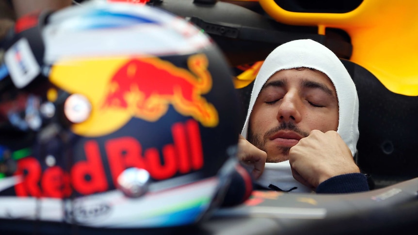 Daniel Ricciardo puts on his hood while sitting in his Red Bull car.