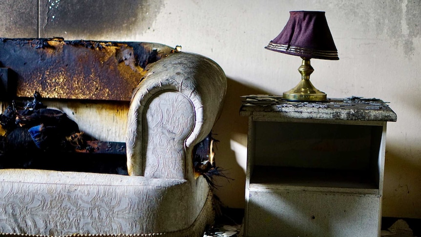 A picture of a couch with fire damage.