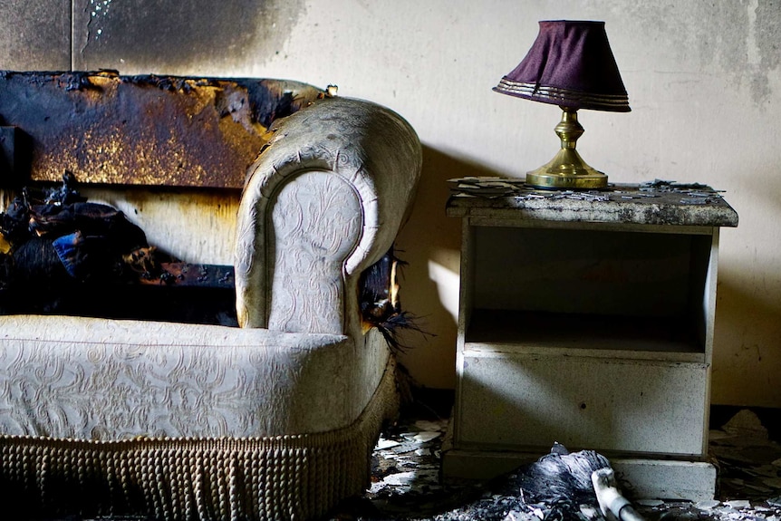 A picture of a couch with fire damage.