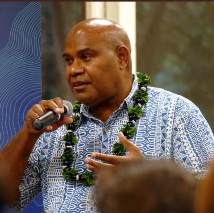 Tarcisius Kabutaulaka wearing a blue pacific themed shirt addressing the room. 
