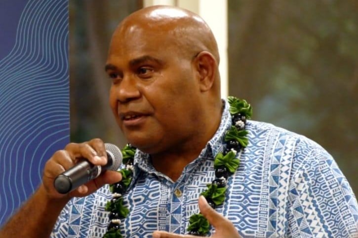 Tarcisius Kabutaulaka wearing a blue pacific themed shirt addressing the room. 