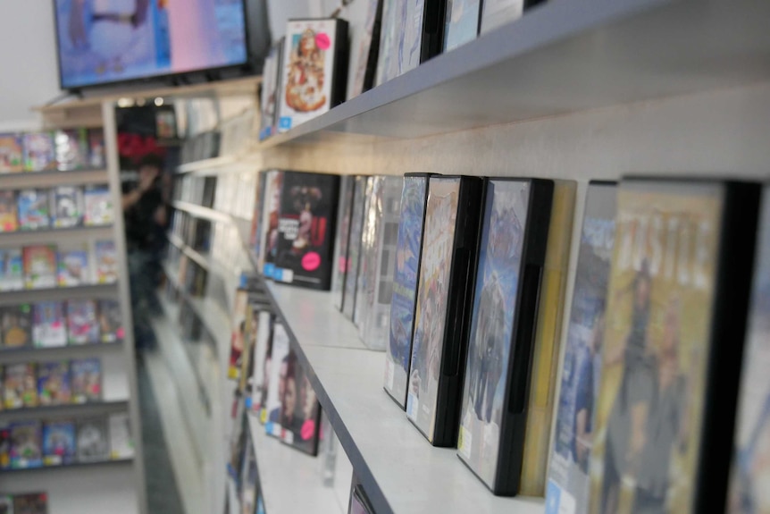 A close-up of DVD cases on a shelf in a video rental shop.