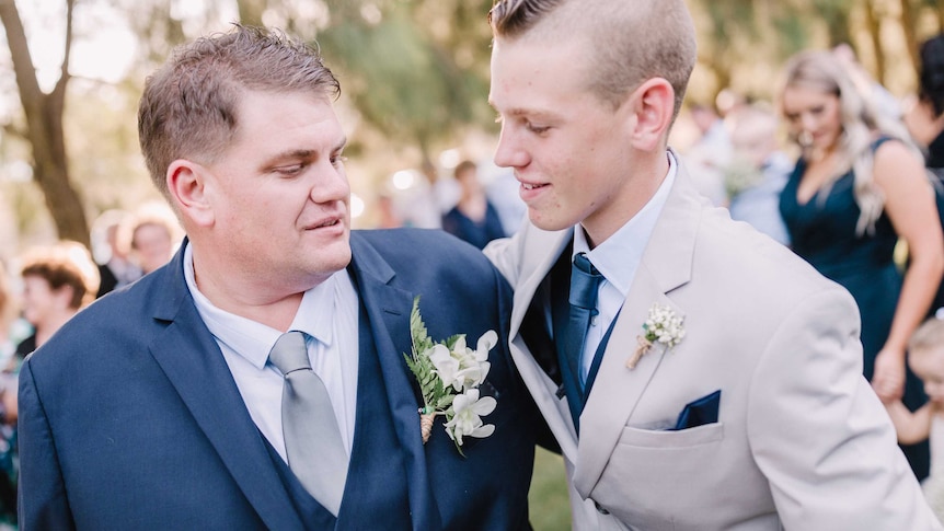 A man and his son, in suits, at a wedding.