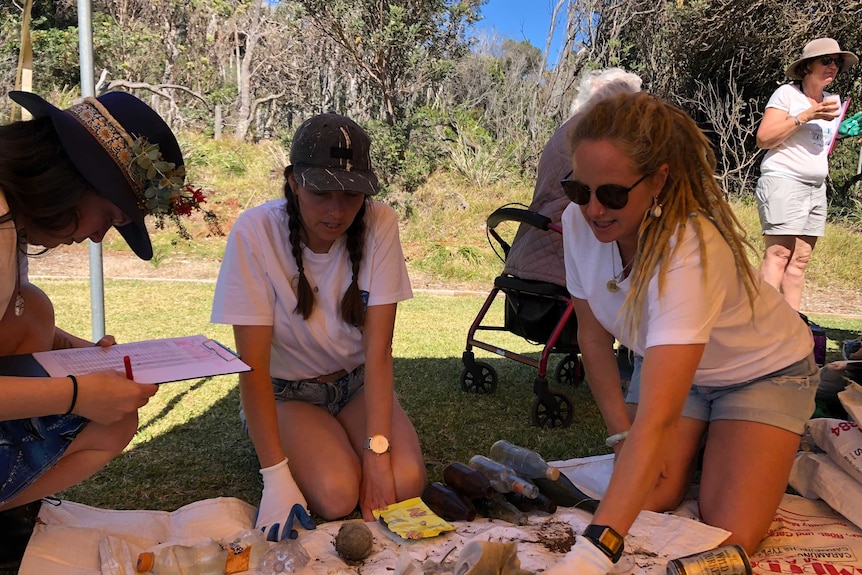 Three women sorting through rubbish.