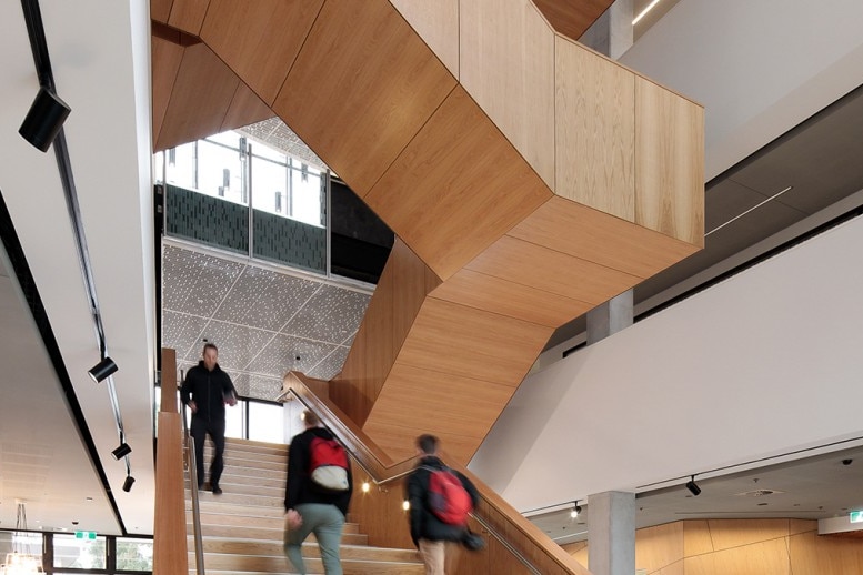 People walk on a staircase in a modern-looking office.