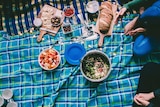 A picnic blanket with food and drink spread out across it.