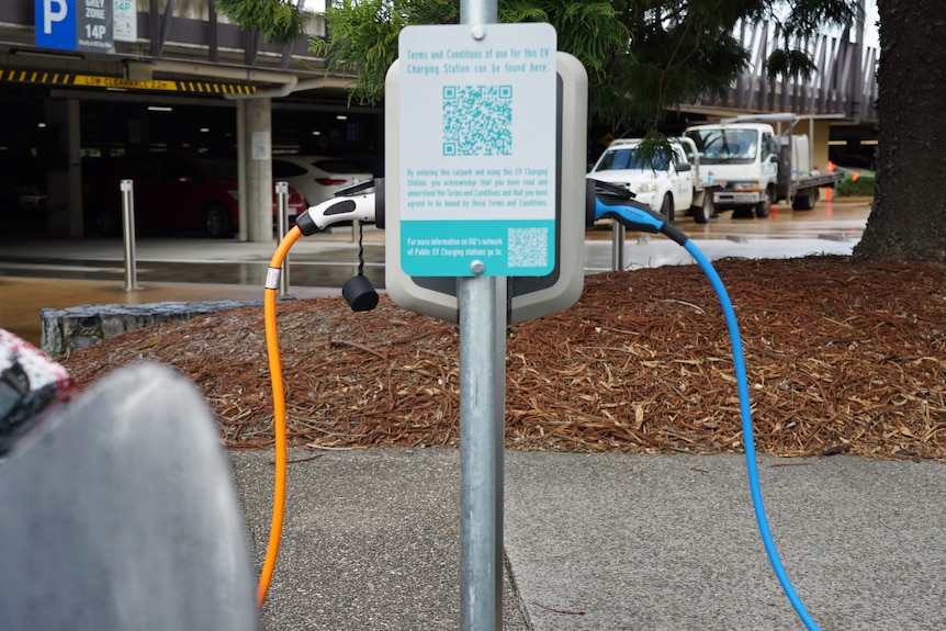 Orange and blue cords plugged into an electric vehicle charging station in Brisbane