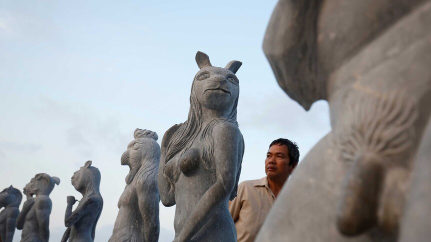 A man is seen in the midst of godlike structures with animal heads and human genitalia.