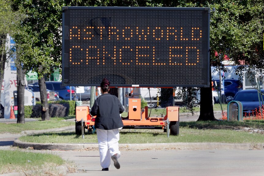 A woman walks towards a sign reading 'Astroworld canceled' 