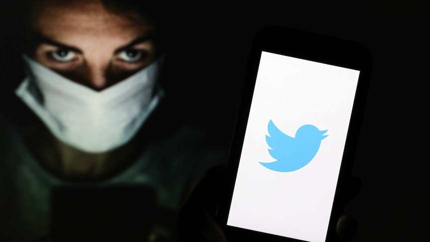 Woman wearing a mask holding phone with Twitter logo