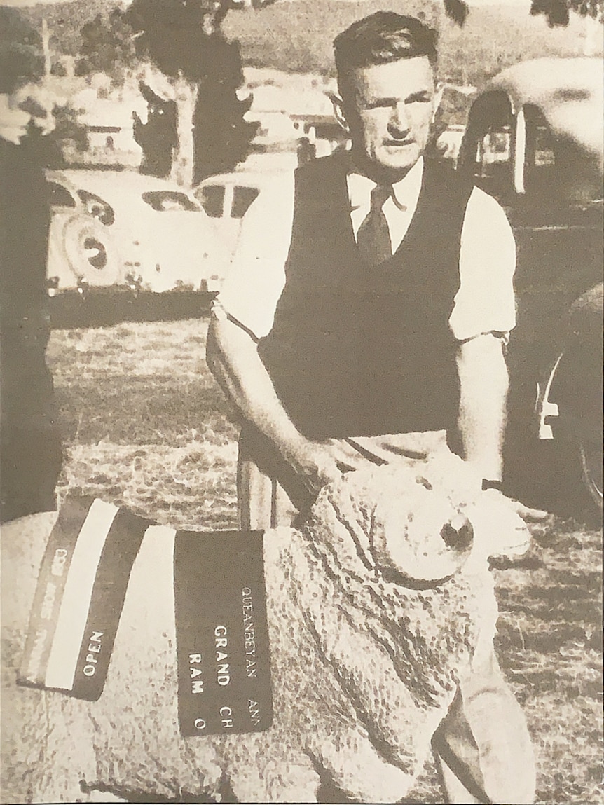 A black and white photo of a man holding a sheep