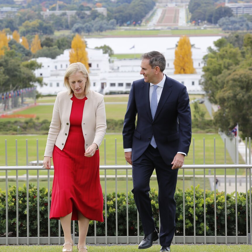 Katy Gallagher and Jim Chalmers walk on the grass on top of Parliament House