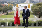 Katy Gallagher and Jim Chalmers walk on the grass on top of Parliament House