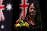 Jane Hayward adds a flower to a map of Victoria at a bushfire commemoration ceremony.