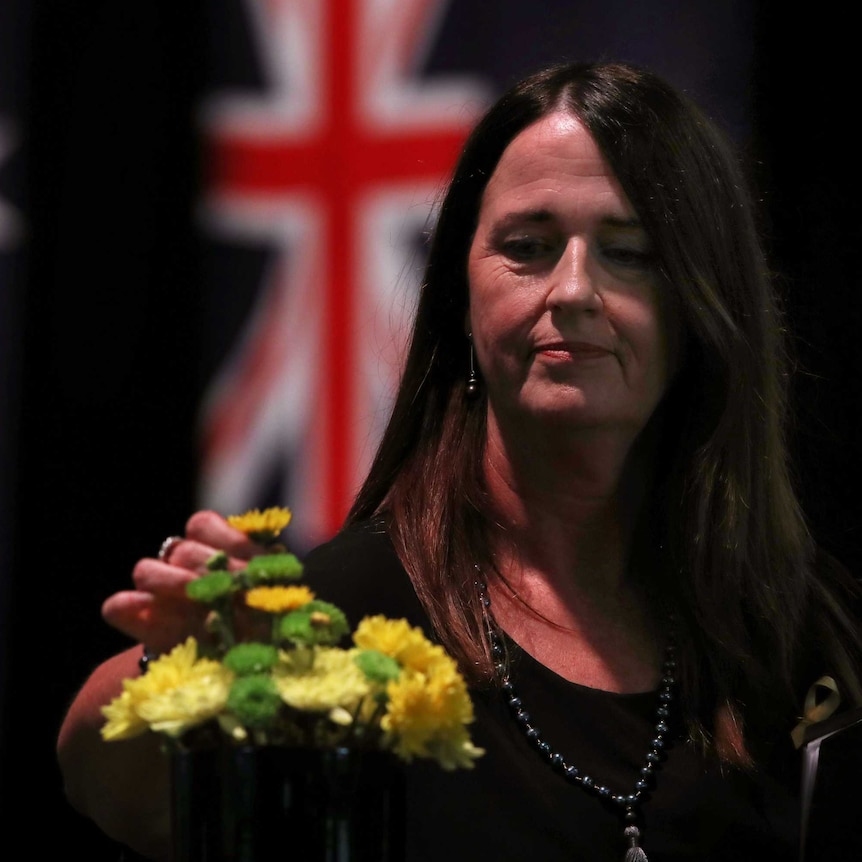 Jane Hayward adds a flower to a map of Victoria at a bushfire commemoration ceremony.