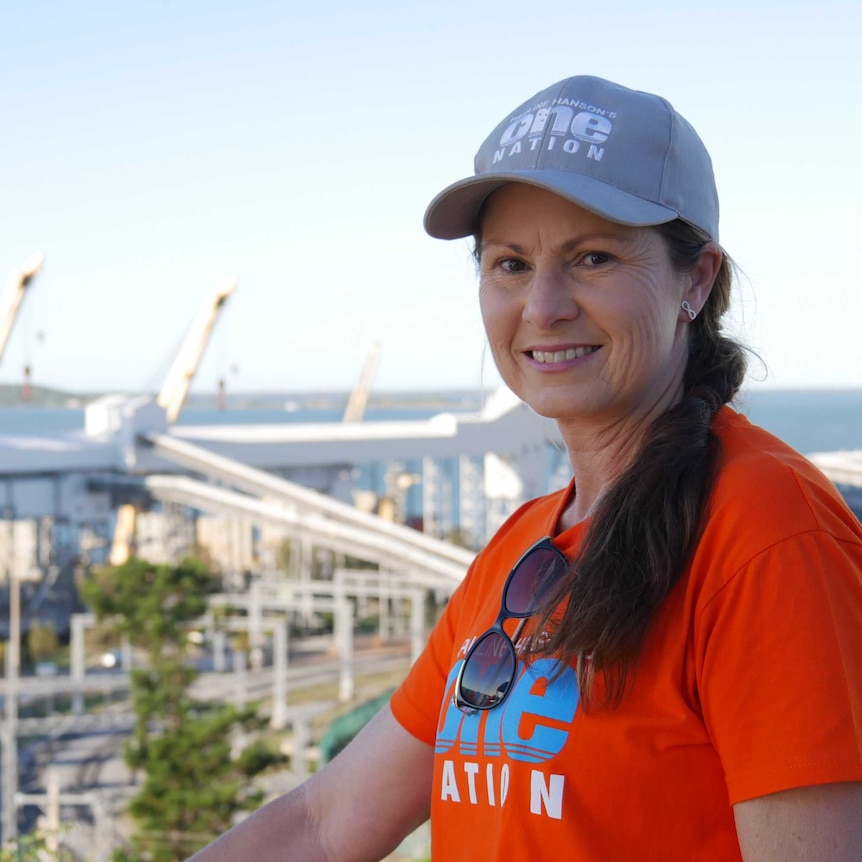 A woman wearing a hat stands in front of a power station in Central Queensland