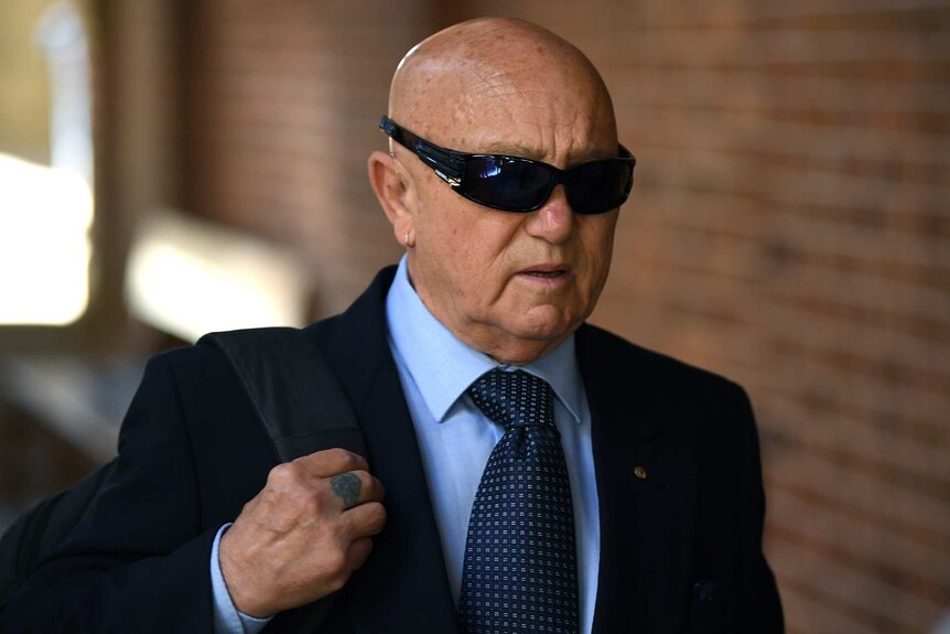 a man in sunglasses walking outside a court