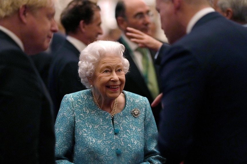 女王微笑着与首相鲍里斯·约翰逊和温莎城堡的另一名男子交谈。