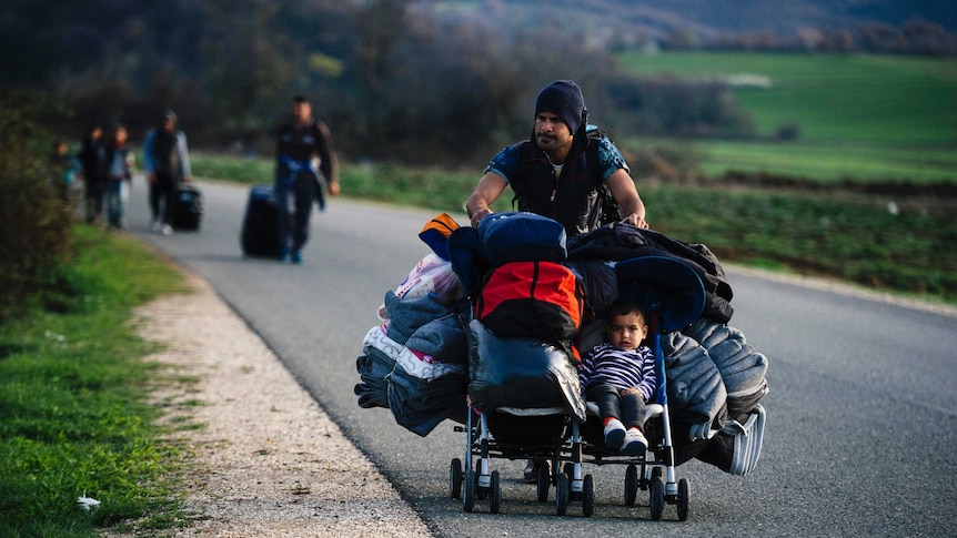 A man pushes his child in a stroller to a makeshift camp.