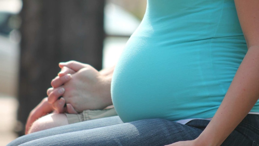 Pregnant woman sitting on park bench.