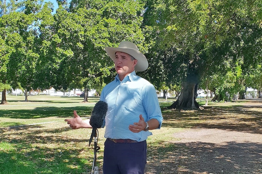 Middled aged man standing at a press conference in a park wearing an akubra hat.
