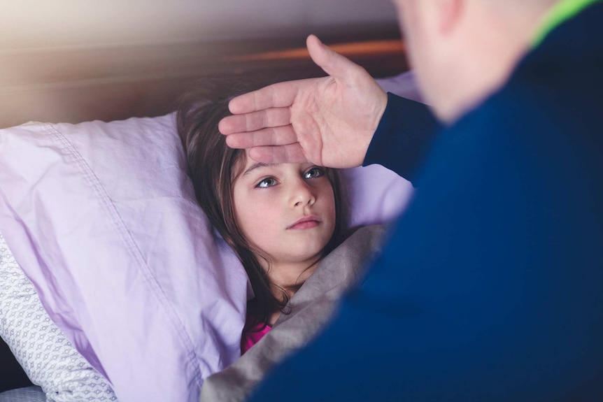 Father checking daughter's forehead for fever