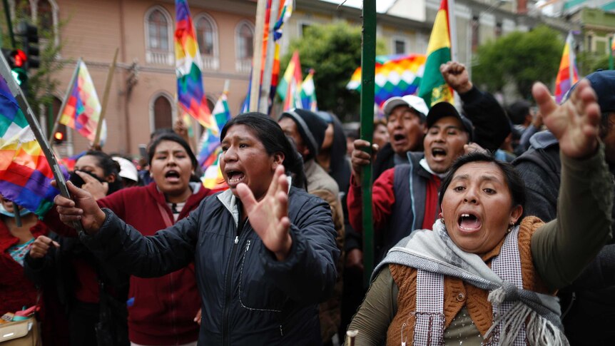 Protesters in the streets of Bolivia with flags.