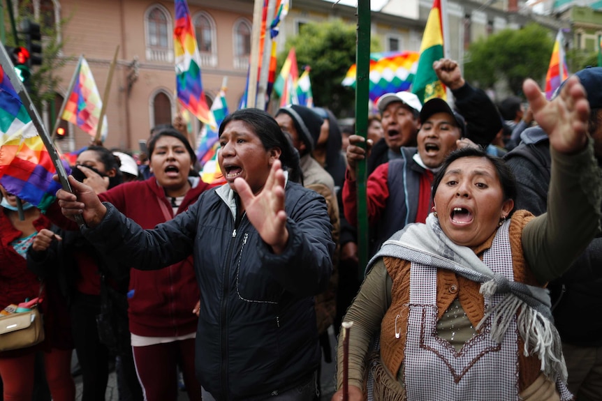 Protesters in the streets of Bolivia with flags.